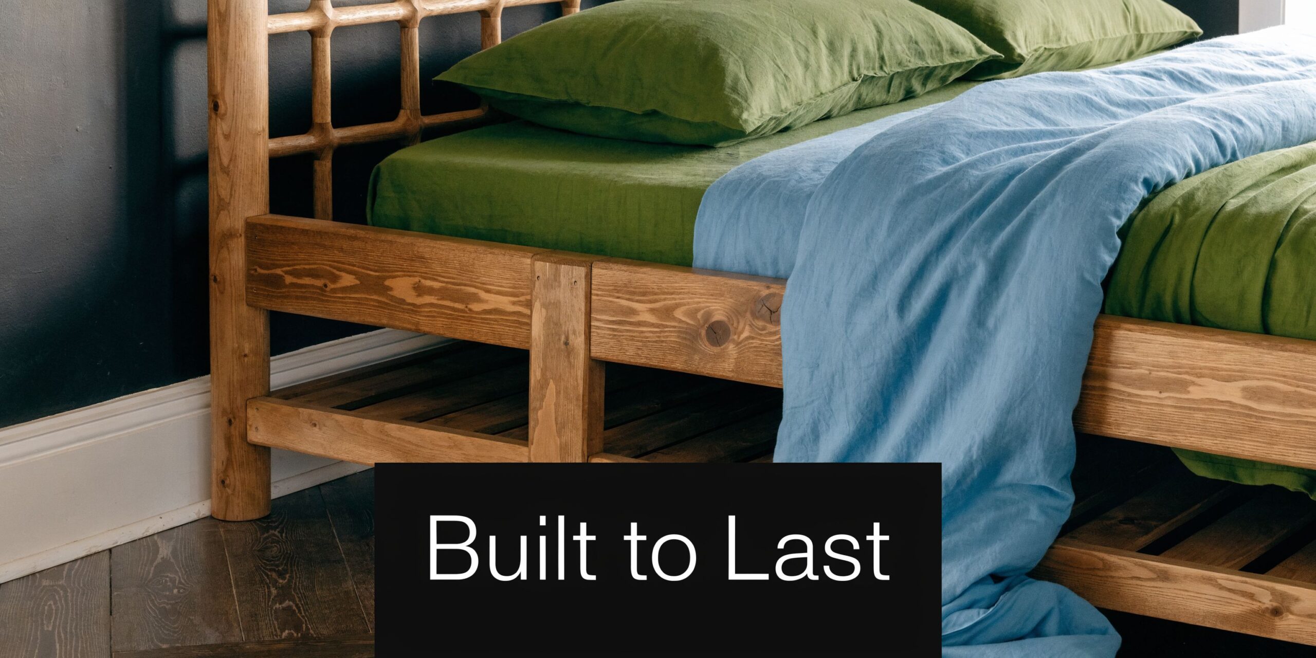 A close-up view of a sturdy wooden bed frame with built-in lower storage shelves featuring green linens.