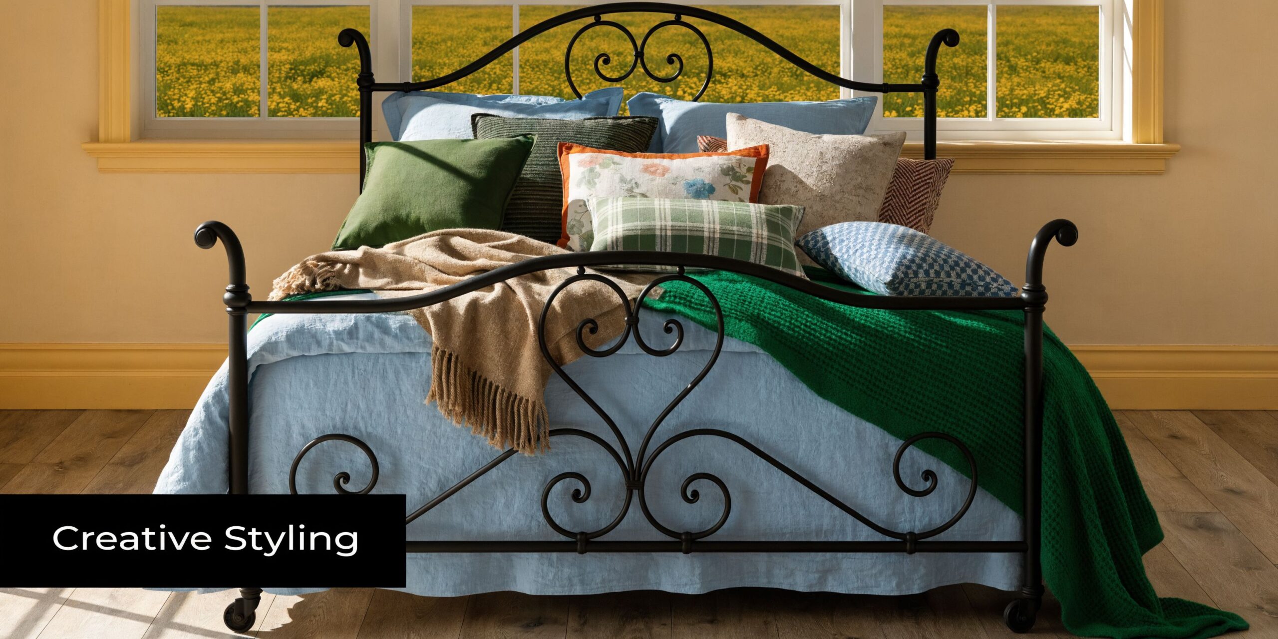 A cozy bedroom featuring a black iron bed decorated with layered pillows and a green throw blanket.