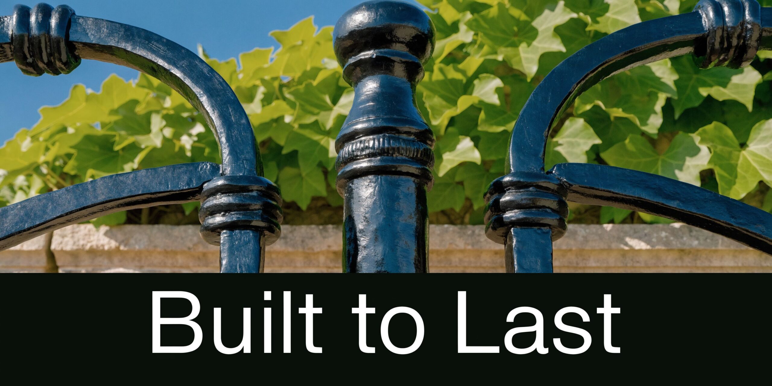 A close-up shot of a sturdy black iron fence with green ivy growing in the background.